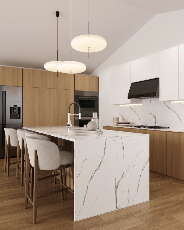 kitchen with custom range hood, pendant lighting, decorative backsplash, white cabinets, and a kitchen island with sink