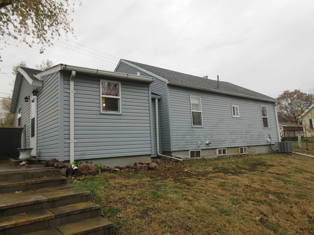 back of property featuring central air condition unit and a lawn