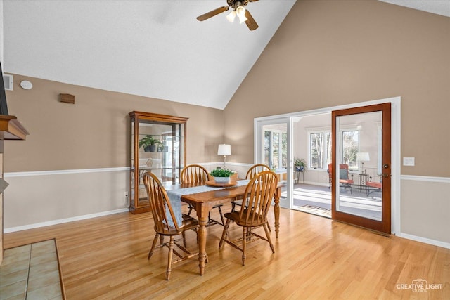 dining space with ceiling fan, light wood-type flooring, and high vaulted ceiling