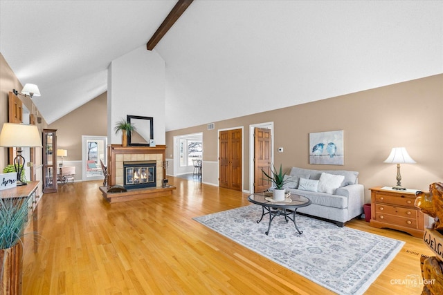 living room with hardwood / wood-style flooring, lofted ceiling with beams, and a fireplace