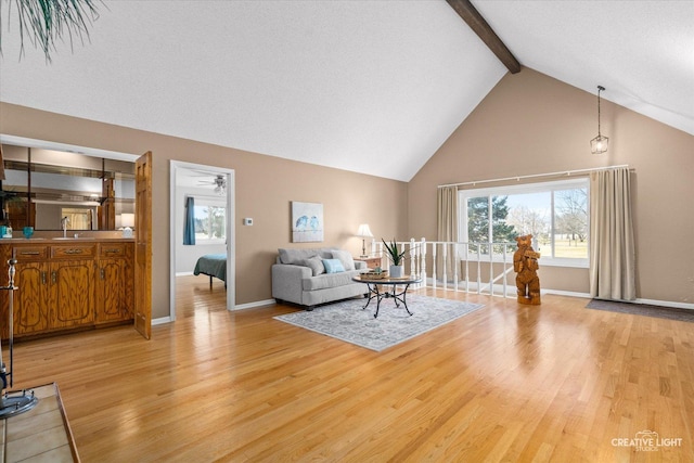 living room featuring vaulted ceiling with beams, light wood-type flooring, and sink