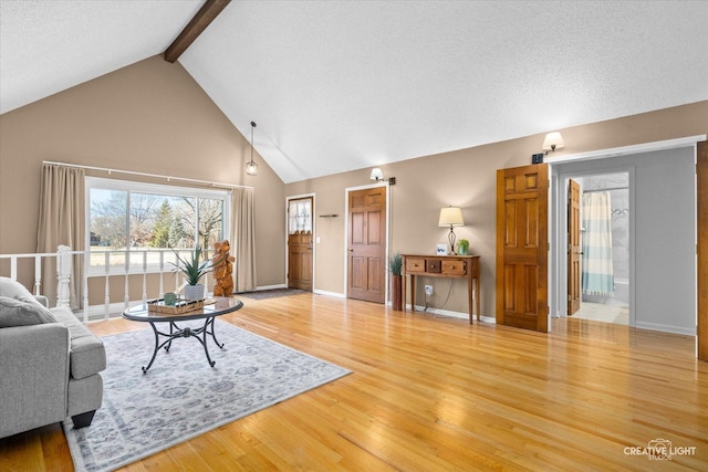 living room featuring lofted ceiling with beams, wood-type flooring, and a textured ceiling