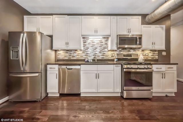 kitchen with white cabinets, backsplash, appliances with stainless steel finishes, dark hardwood / wood-style floors, and sink