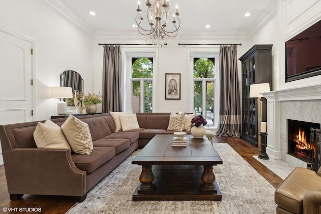 living room with a premium fireplace, ornamental molding, dark hardwood / wood-style floors, and an inviting chandelier