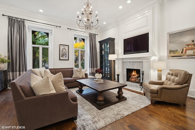 living room featuring dark hardwood / wood-style flooring, ornamental molding, a premium fireplace, and an inviting chandelier