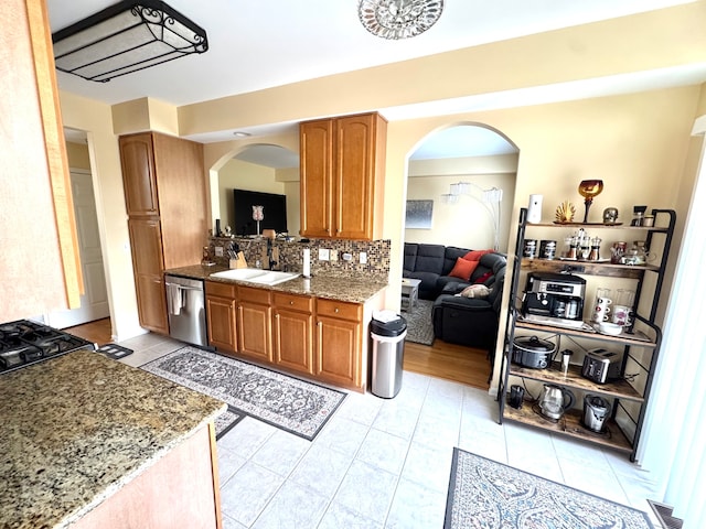 kitchen featuring backsplash, stone counters, dishwasher, and sink