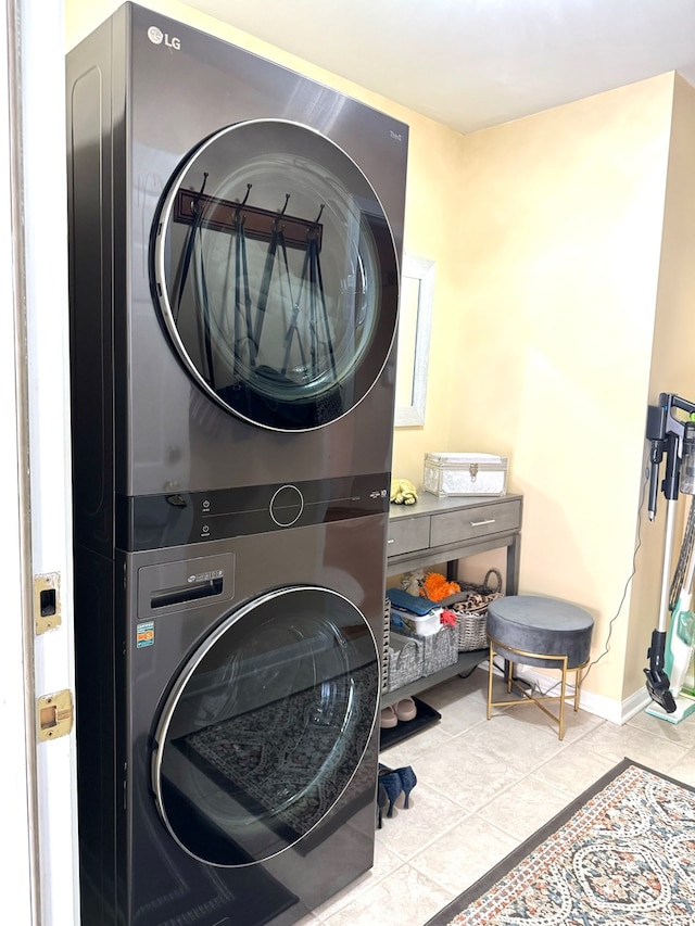 laundry room with stacked washer and dryer and light tile patterned flooring