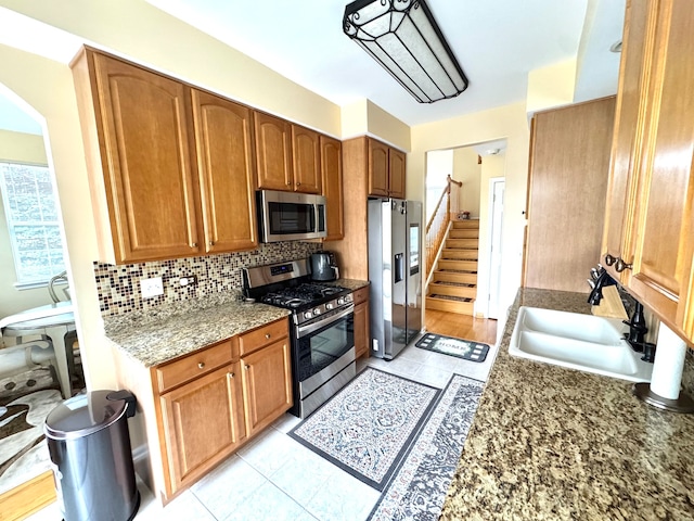 kitchen with stone countertops, sink, stainless steel appliances, and tasteful backsplash