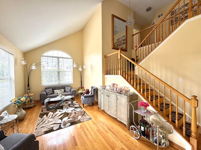 living room featuring high vaulted ceiling, a healthy amount of sunlight, and light wood-type flooring