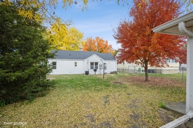 back of property featuring central AC and a yard