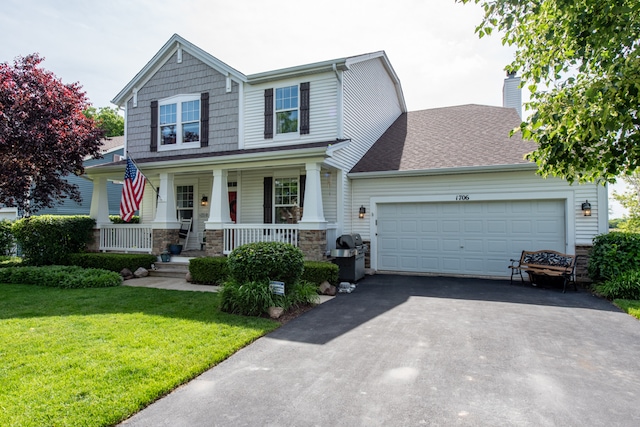 view of front of property with a garage, a front lawn, and a porch