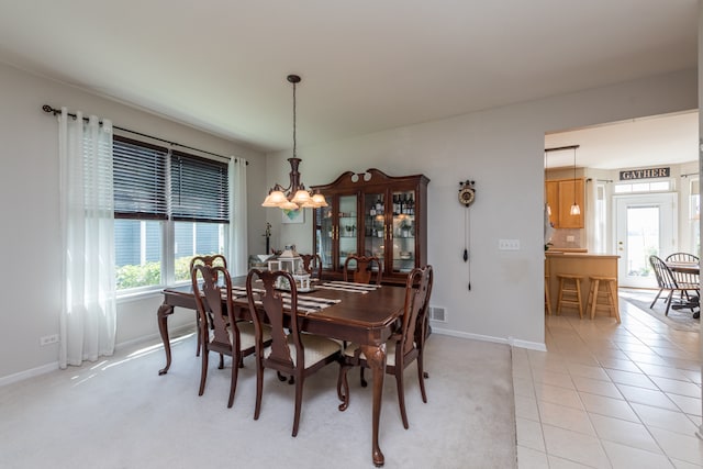 dining space featuring light tile patterned flooring, a healthy amount of sunlight, and a chandelier