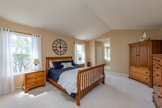 bedroom with connected bathroom, vaulted ceiling, multiple windows, and light colored carpet