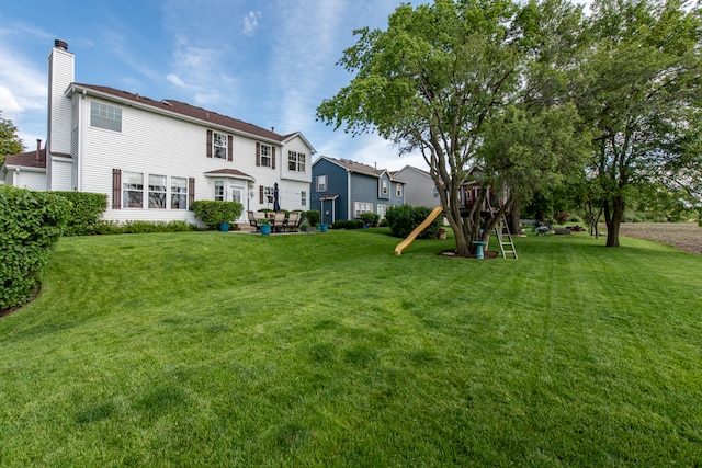 rear view of property featuring a playground and a yard