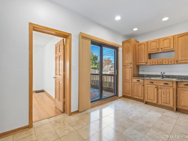 kitchen featuring light wood-type flooring, sink, and dark stone counters