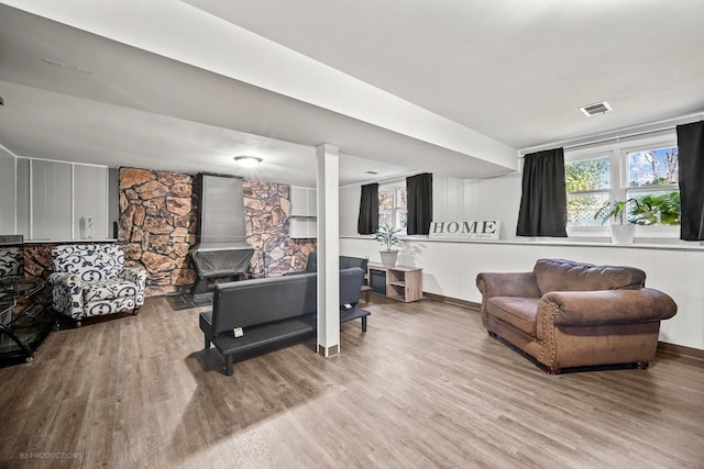 living room with a wood stove and light hardwood / wood-style flooring