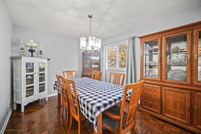 dining space featuring a chandelier and dark parquet flooring