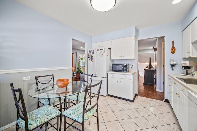 kitchen with white cabinets, light wood-type flooring, sink, and white appliances