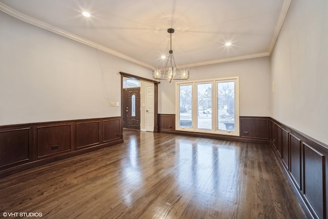 empty room featuring dark wood-type flooring, crown molding, and an inviting chandelier