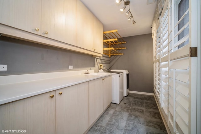 washroom featuring sink, rail lighting, washer and clothes dryer, and cabinets