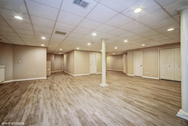 basement featuring a paneled ceiling and light hardwood / wood-style flooring