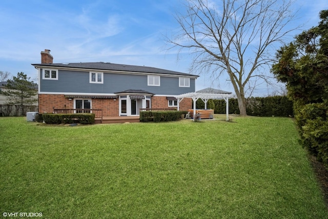 rear view of property featuring a hot tub, a yard, a deck, and a pergola