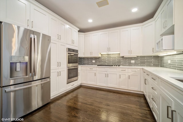 kitchen featuring tasteful backsplash, stainless steel appliances, dark hardwood / wood-style flooring, and white cabinets