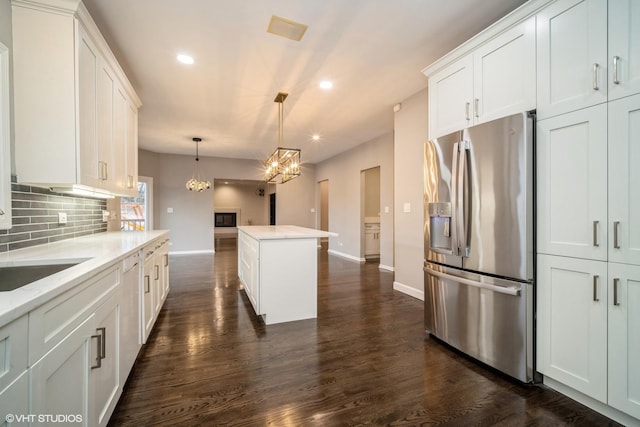 kitchen with white cabinetry, a center island, stainless steel fridge with ice dispenser, hanging light fixtures, and decorative backsplash