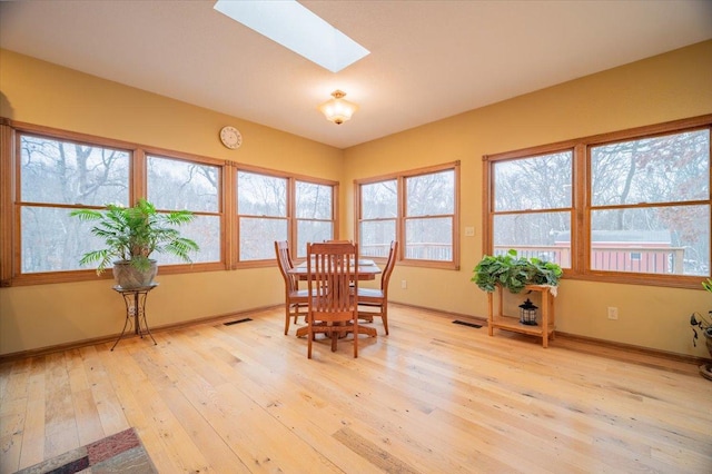 dining space with a skylight, a wealth of natural light, and light hardwood / wood-style flooring