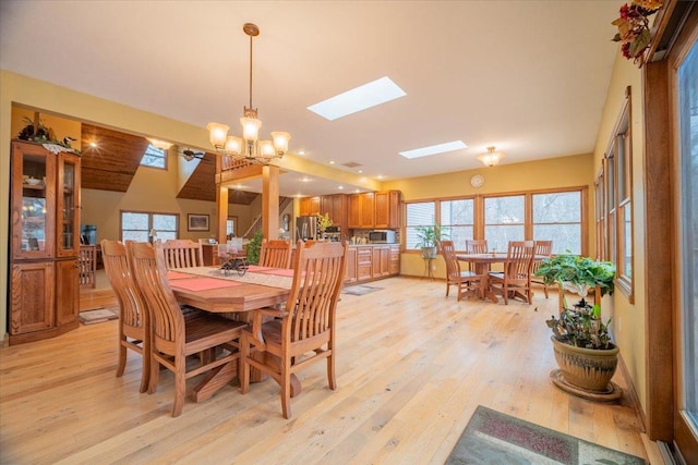 dining space featuring a chandelier, light hardwood / wood-style floors, and a skylight