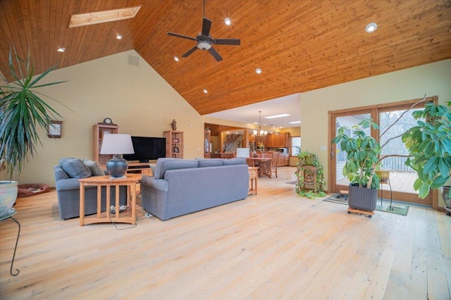 living room featuring light wood-type flooring, a skylight, wood ceiling, ceiling fan with notable chandelier, and high vaulted ceiling