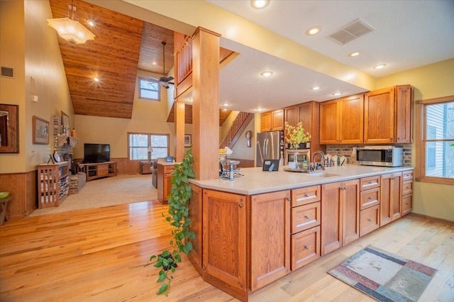 kitchen with stainless steel appliances, ceiling fan, sink, high vaulted ceiling, and light hardwood / wood-style flooring