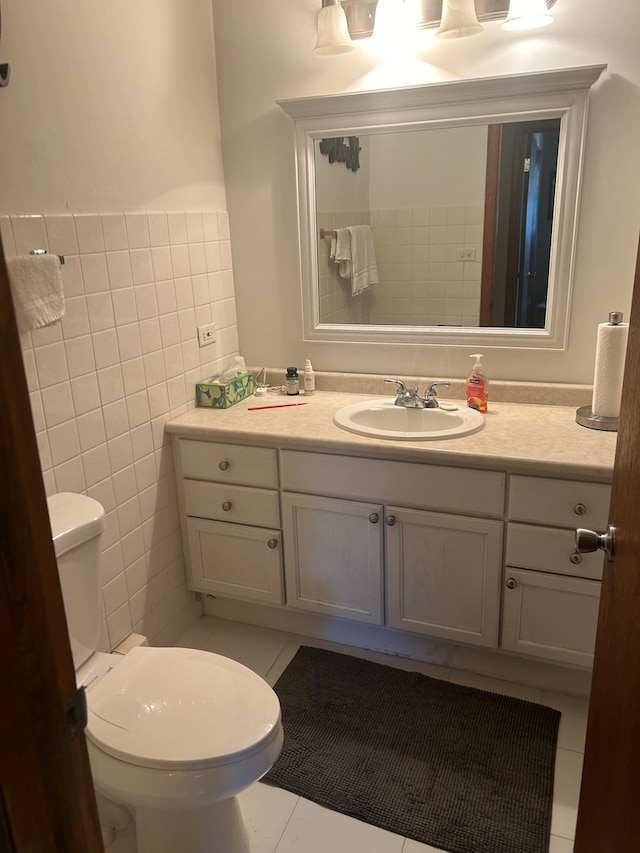 bathroom featuring toilet, vanity, tile patterned floors, and tile walls