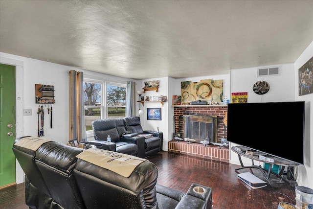 living room with a brick fireplace, visible vents, and wood-type flooring