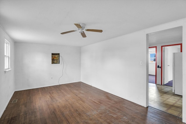 spare room featuring wood finished floors, visible vents, and ceiling fan