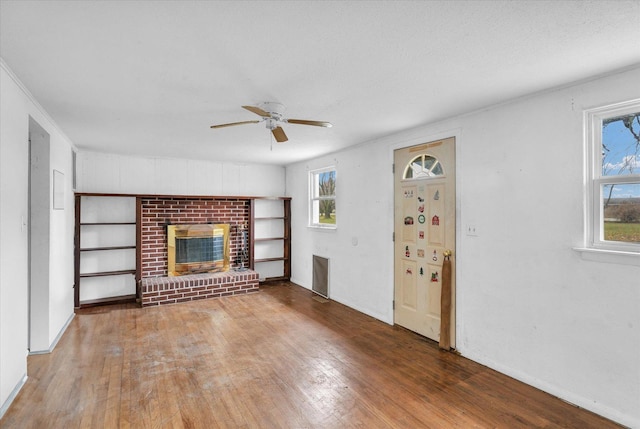 unfurnished living room featuring ceiling fan, a textured ceiling, wood finished floors, and a fireplace