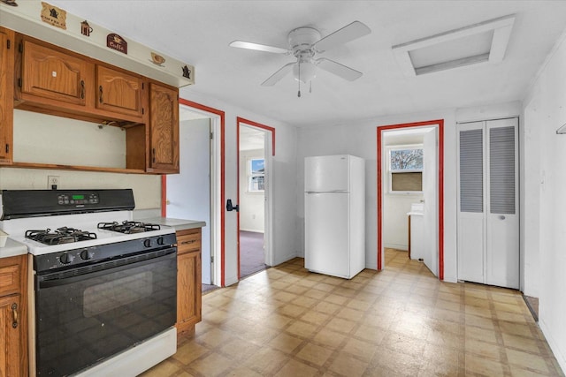 kitchen featuring range with gas cooktop, light countertops, light floors, and freestanding refrigerator