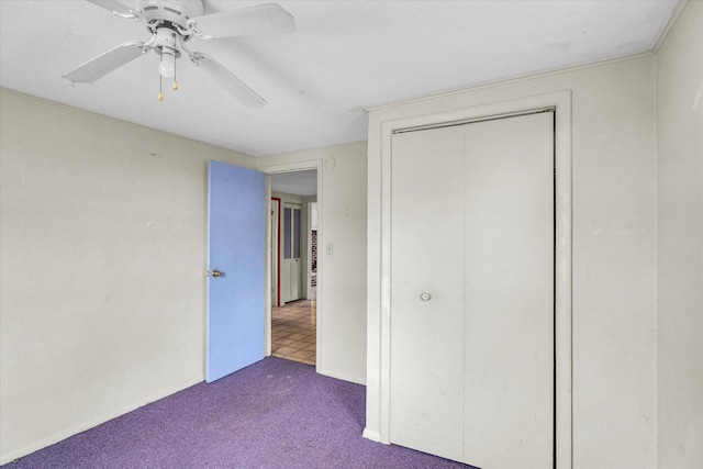 unfurnished bedroom featuring dark colored carpet, a closet, and ceiling fan