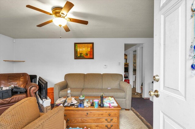 carpeted living room with ceiling fan, a fireplace, and a textured ceiling