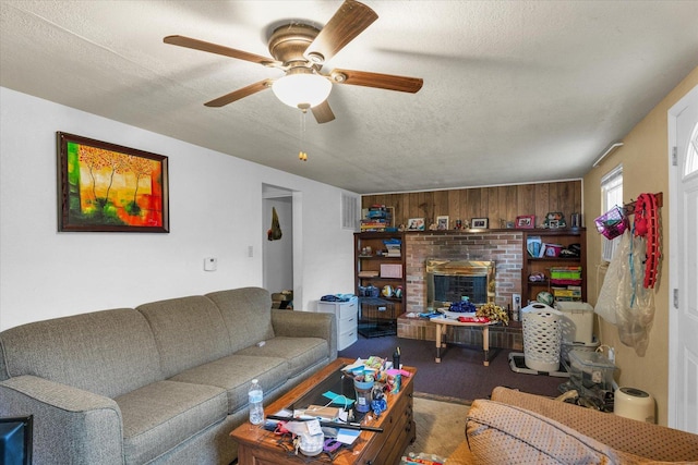 carpeted living area with a brick fireplace, a textured ceiling, and a ceiling fan