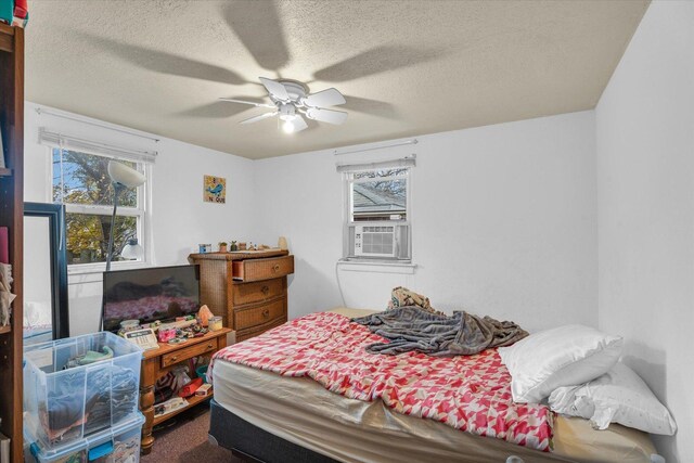 carpeted bedroom featuring multiple windows, ceiling fan, cooling unit, and a textured ceiling