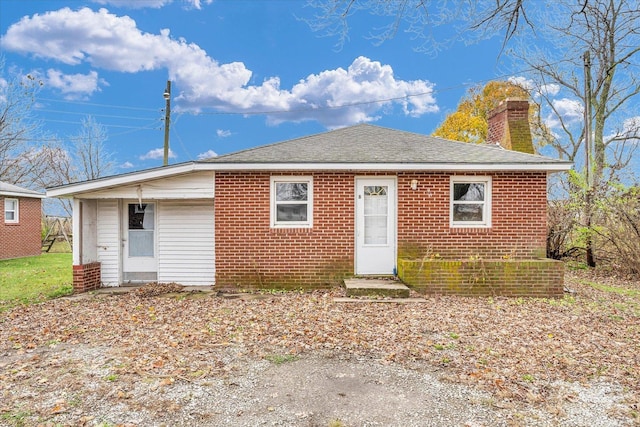 view of front of home with brick siding, a chimney, and a shingled roof