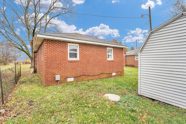 view of side of home with crawl space, a lawn, brick siding, and fence