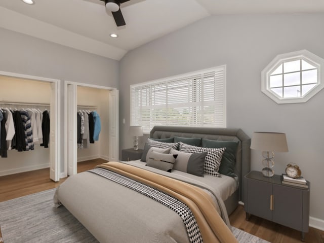 bedroom featuring two closets, dark wood-type flooring, vaulted ceiling, and ceiling fan