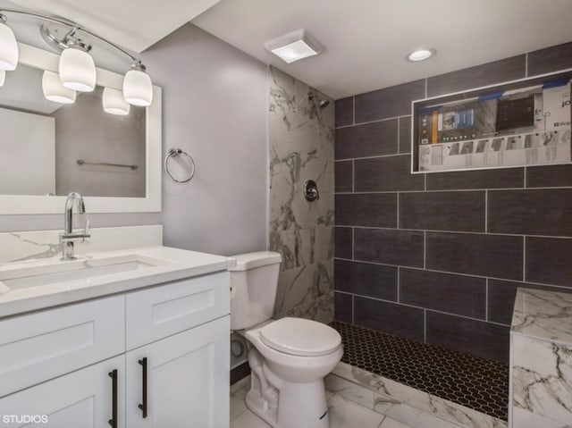 bathroom with toilet, vanity, and tiled shower