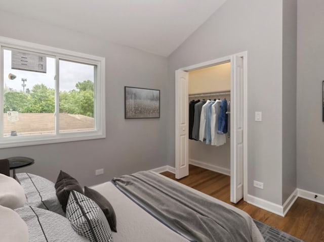 bedroom with a closet, lofted ceiling, and dark hardwood / wood-style flooring