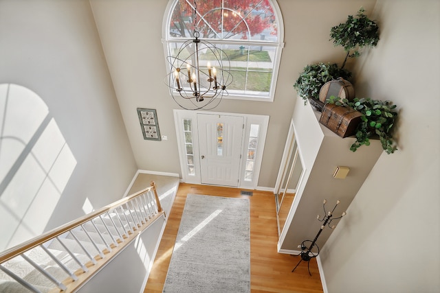 foyer entrance featuring a chandelier, a towering ceiling, and light hardwood / wood-style flooring