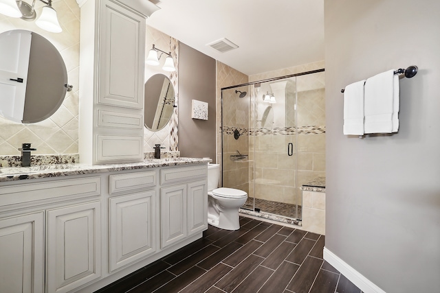 bathroom featuring vanity, toilet, and a shower with shower door