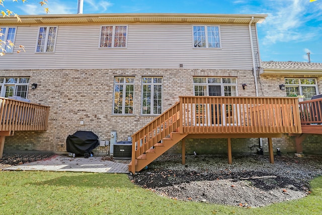 back of property featuring central air condition unit, a wooden deck, and a patio