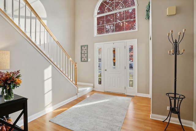 entryway featuring a towering ceiling and light wood-type flooring